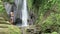 Aerial view back of woman looking at the beautiful waterfall in green tropical rain forest in Bali