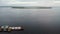 Aerial view. A barge moored to the shore of a wide river near the island at sunset. Cargo ship transporting sand on a navigable ri