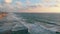 Aerial view of the beach and the promenade of Tel Aviv at sunset, with resting people and surfers riding the waves of the Mediterr