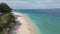 Aerial view of beach with turquoise clear ocean water and white sand beach and greenery on coastline of tropical island