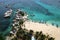 Aerial view of beautiful beach with blue clear water, bunch of artistic rocks, couple of boats and coconut tree