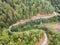 Aerial view of a beautiful curvy road and the green woods of high mountains