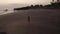 Aerial view of beautiful girl in bikini on the black beach at sunset