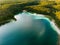 Aerial view of beautiful green waters of lake Gela. Birds eye view of scenic emerald lake surrounded by pine forests