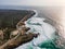 Aerial view of a beautiful isolated road with vehicles driving along south Portuguese coastline facing the Atlantic Ocean rough