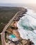 Aerial view of a beautiful isolated road with vehicles driving along south Portuguese coastline facing the Atlantic Ocean rough