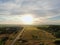 Aerial view beautiful panoramic landscape golden sunset above the forest. The road goes beyond the horizon in the rays of the sun