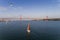 Aerial view of a beautiful sail boat on the Tagus River with the 25 of April Bridge on the background, in the city of Lisbon, Port