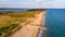 An aerial view of a beautiful sandy beach along blue water sea and amaizing cliffs in the background at golden hour under a