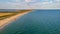 An aerial view of a beautiful sandy beach along blue water sea and amaizing cliffs in the background at golden hour under a