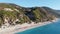 Aerial view of beautiful sandy beach with sunshades and soft turquoise ocean wave. Para glider is flying over tropical sea in