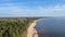 Aerial view of beautiful sea landscape. Drone view of a sandy beach, green trees and silent sea in a sunny day with blue sky.