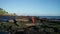 Aerial view of beautiful sensual woman in bikini and red overall posing on the rocks near black sand beach