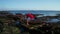 Aerial view of beautiful sensual woman in bikini and red overall posing on the rocks over sea and sky background