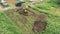 Aerial view of the beginning of new house construction. Clip. Tractor is dogging a hole for the house foundation in the