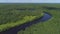 Aerial view of the bend of the river surrounded by green fields through which the river flows. Shot. Natural landscape