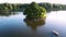 Aerial view of a big pond with island surrounded by calm water, people having fun, riding boats and catamarans, beauty