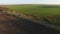 Aerial view of black car moving on the road countryside sunset green fields