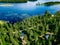 Aerial view of blue lake with green forests in Finland. Wooden house, sauna, boats and fishing pier by the lake