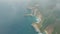 Aerial view of blue ocean, waves, tropical island with mountains through clouds