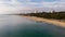 An aerial view of the Boscombe Beach with sandy beach, calm flat water, groynes breakwaters, grassy cliff and building in the