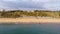 An aerial view of the Boscombe Beach with sandy beach, calm flat water, groynes breakwaters, grassy cliff and building in the