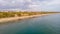 An aerial view of the Boscombe Beach with sandy beach, calm flat water, groynes breakwaters, grassy cliff and building in the