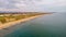 An aerial view of the Boscombe Beach with sandy beach, calm flat water, groynes breakwaters, grassy cliff and building in the