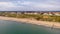 An aerial view of the Boscombe Beach with sandy beach, calm flat water, groynes breakwaters, grassy cliff and building in the