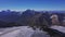 Aerial view of breathtaking high range of mountains on blue sky background. Clip. Flying over the giant hills with snowy