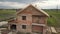 Aerial view of a brick house with wooden roof frame under construction.