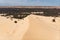 Aerial view of brown winding sand dunes with four-wheel car