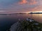 Aerial view of a building at the edge of a rocky coast at a mesmerizing pink sunset