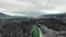 Aerial view camera moving over a dense dark pine forest with an emerald river at the foot of the mountain on a frosty winter day