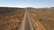 Aerial view of car driving down a long dirt road