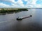 Aerial view cargo merchant ship sails along the river. Transport of goods by river barges. Beautiful landscape of the river