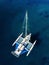 Aerial view of catamaran anchoring on coral reef.