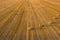 Aerial view of cereal fields after the harvest. There is haystack and tractor tread