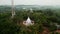 Aerial view circles temple, towering communications mast amidst lush tropical island greens. Historical spiritual site