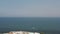 Aerial view of the clear blue sea water and small summer hotels near the seashore against blue cloudy sky in warm summer