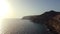 Aerial view of cliff at sunset with houses and rock walls, sun on the horizon. Gran Canaria, Arguineguin