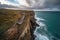 aerial view of cliffside walkway, with dramatic ocean and sky in the background