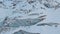 Aerial view close-up edge of a flowing glacier covered with snow and stones high in the mountains. Natural destruction