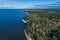 Aerial view of the coastline of the Gulf of Finland. Sandy coast and forest belt. Treetops, blue sky.