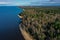 Aerial view of the coastline of the Gulf of Finland. Sandy coast and forest belt. Treetops, blue sky.