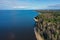 Aerial view of the coastline of the Gulf of Finland. Sandy coast and forest belt. Treetops, blue sky.