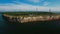 Aerial view of the coastline with rocks from the sea and on the land old lighthouse and wind turbine.