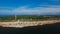 Aerial view of the coastline with rocks from the sea and on the land old lighthouse and wind turbine power.