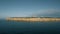 Aerial view of the coastline with rocks from the sea and on the land old lighthouse and wind turbine power generators.