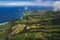 Aerial view of the coastline on Sao Miguel Island, with town buildings, green farmland and volcanic mountains, Azores, Portugal